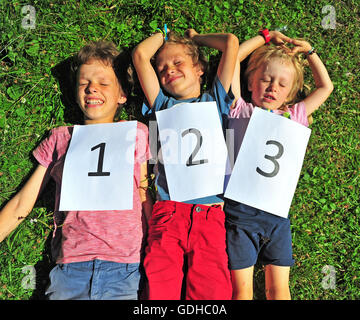 Three kids luying on the grass Stock Photo