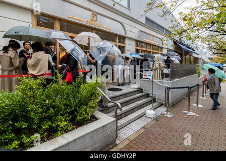 People taking cover on rainy day in Tokyo Japan near main railway station Stock Photo