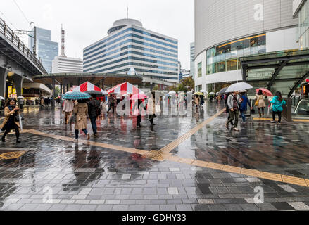 People taking cover on rainy day in Tokyo Japan near main railway station Stock Photo