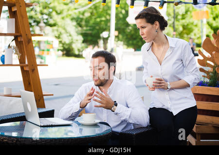 Business Team man and woman at Cafe having a conversation using laptop. Working Meeting Concept Stock Photo