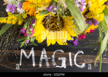 Word Magic with Summer Flowers on a Rustic Wooden Background. Stock Photo