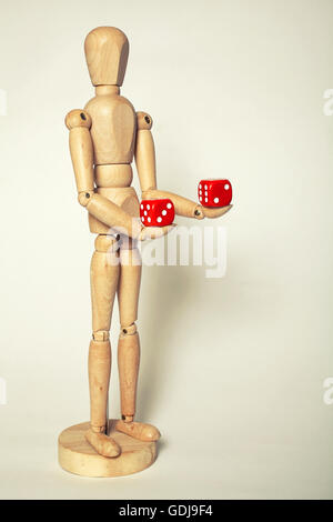 Wooden puppet holds dice on white background Stock Photo