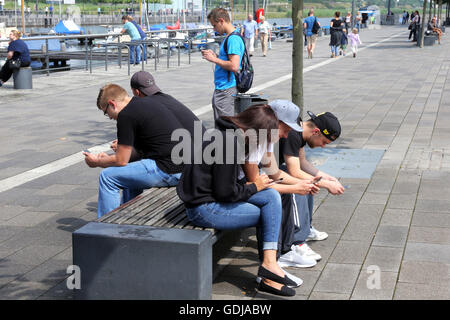 POKEMON GO, young people play the new Nintendo game Pokémon go on their smartphones on Lake Phoenix in Dortmund, Germany. The players try to catch in the real world virtual Pokemon monsters on to their smartphone devices. Stock Photo