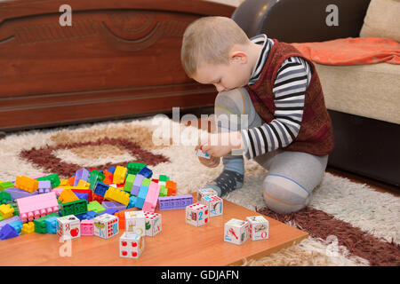 boy playing with blocks and train on the floor Stock Photo