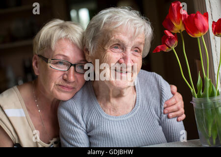 Happy elderly woman with her daughter in behind an embrace. Stock Photo