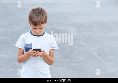 Boy with phone playing game, using application. Outdoor. Childhood, technology leisure concept Stock Photo