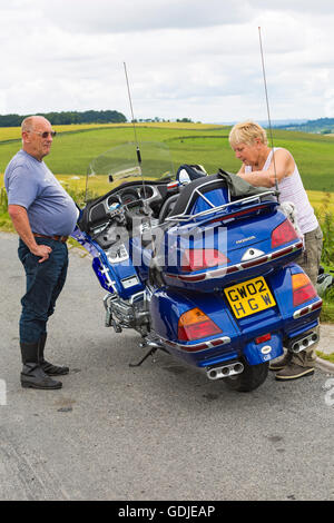 Couple stop on their Honda Goldwing motorbike for a bite to eat and admire the views at Cranborne Chase, Dorset in July Stock Photo