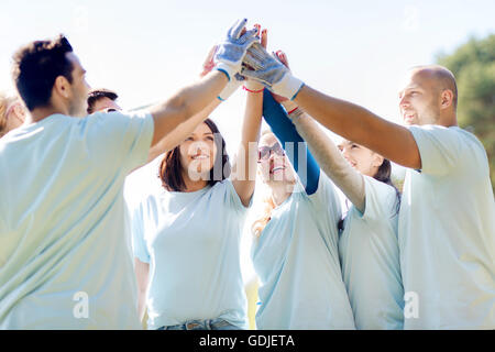 group of volunteers making high five in park Stock Photo