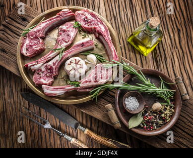 Raw lamb chops with garlic and herbs on the old wooden table. Stock Photo
