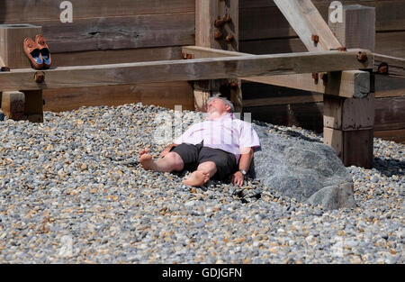mature man laying on sheringham shingle beach Stock Photo