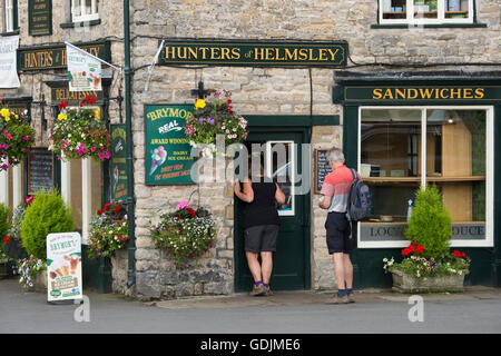 Couple buy ice creams through the hatch at Hunters of Helmsley, an independent delicatessen - Helmsley, North Yorkshire, GB. Stock Photo