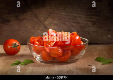 Sliced tomatoes in bowl on old rustic wooden background Stock Photo