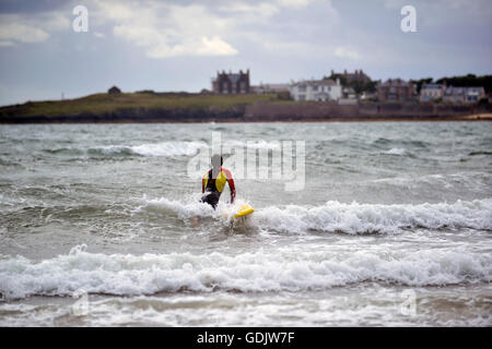 RNLI lifeguard patrols the waters on Harbour beach in the Fife coastal village of Elie. Stock Photo