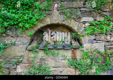 Old boots and wine bottles in recess of stone wall Camogli Italy Stock Photo