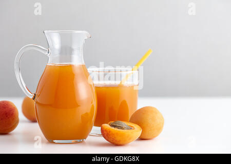 Ripe apricots and a glass jug with fresh juice Stock Photo