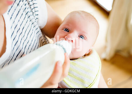 Unrecognizable mother feeding baby son, milk in bottle, close up Stock Photo