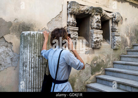 France. Arles. A young woman speaks on a mobile phone next to some Roman remains Stock Photo