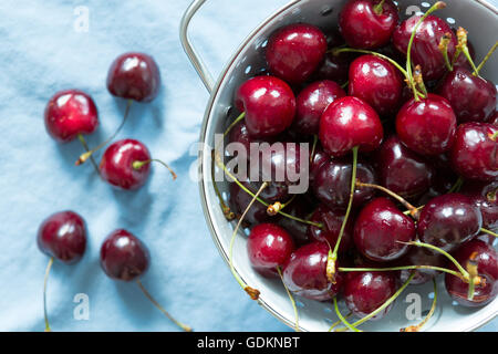 Cherries in bowl on blue tablecloth. summerfeeling Stock Photo