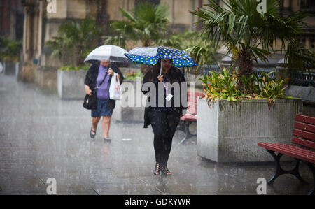 Heavy rain in Manchester city centre    Rain raining down pour  wet soaked soaking through  umbrella bouncing of floor pavement Stock Photo