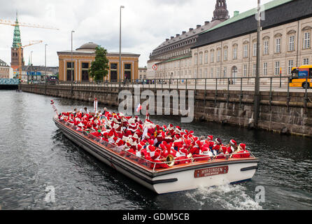 Copenhagen, Denmark – July 18, 2016: Santa’s participating in in the World Santa Claus Congress 2016 are transported by boat to the inner city of Copenhagen where they will walk in parade through the main shopping area, Stroeget to the City Hall. At the photo the Santa’s are sailing on the canal next to the Parliament, Christiansborg (R). The congress has taken place since 1957. The venue and organizer is Bakken, the world’s oldest amusement park and located north of Copenhagen. Credit:  OJPHOTOS/Alamy Live News Stock Photo