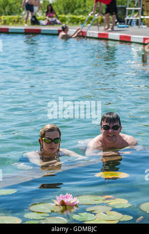 London, UK.  19 July 2016.  Local office workers on their lunch break, Evelyn and Sean, enjoy the cooling waters of King's Cross pond on the hottest day of the year so far, with temperatures expected to reach 35C in the capital.  The UK's first ever man-made fresh water public bathing pond is a piece of innovative Land Art, within a working construction site area of London's King's Cross designed by Ooze architects. © Stephen Chung / Alamy Live News Stock Photo