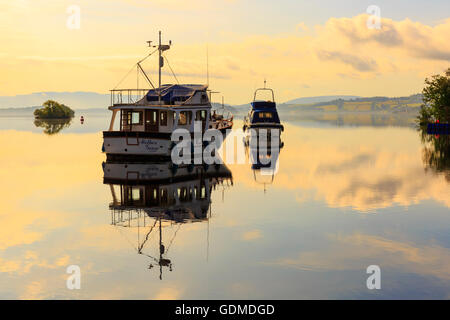On what was to be the warmest day of the summer, the settled weather conditions make for a beautiful sunrise over the calm waters of Loch lomond, near Glasgow, Scotland, UK Stock Photo