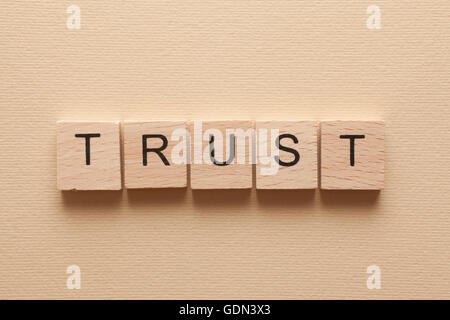 Wooden letters spelling TRUST on beige background Stock Photo