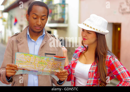 Interracial happy couple wearing casual clothes in urban envrionment, interacting and looking at map Stock Photo