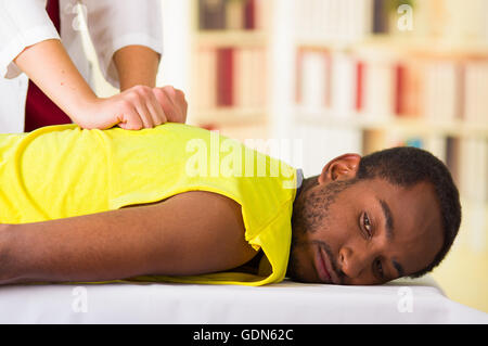 Man getting physical treatment from physio therapist, her hands working on his back and applying massage, medical concept Stock Photo