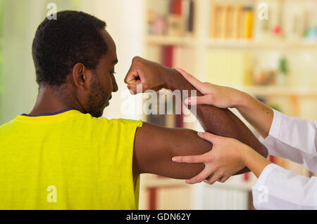 Man getting physical arm treatment from physio therapist, her hands working on his shoulder and elbow, medical concept Stock Photo