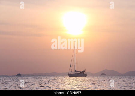 Sailing yaht in open sea on beautiful sunset sky background Stock Photo