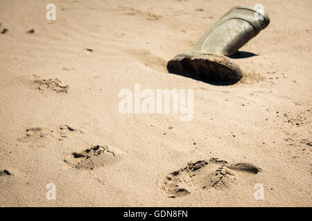 Human footprint by lost wellington boot on a beach. Stock Photo