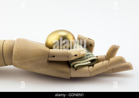 Golden nest egg in palm of wooden hand with dollar notes isolated on white Stock Photo