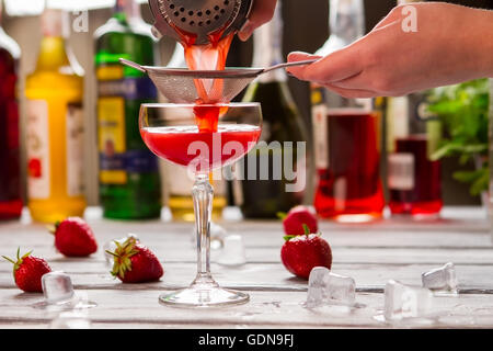 Red drink pours through sieve. Stock Photo