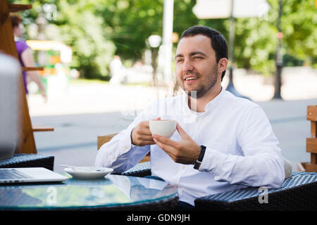Confident successful businessman in suit enjoying a cup of coffee while having work break lunch in modern restaurant,young intelligent man or entrepreneur relaxing in outdoors cafe looking pensive Stock Photo