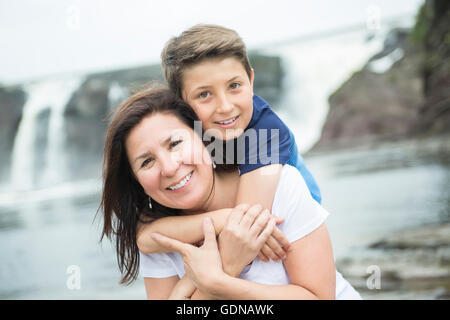 mother and son playing in front of a waterfall Stock Photo