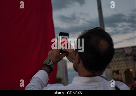 A Turkish man using a mobile phone to photograph a Turkish flag at a pro government rally to celebrate a failed coup attempt Stock Photo