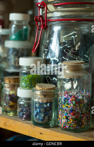 Selection of vintage sewing accessories and haberdashery in jars on a wooden shelf display Stock Photo