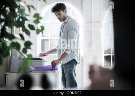 Male designer using fax machine in design studio Stock Photo