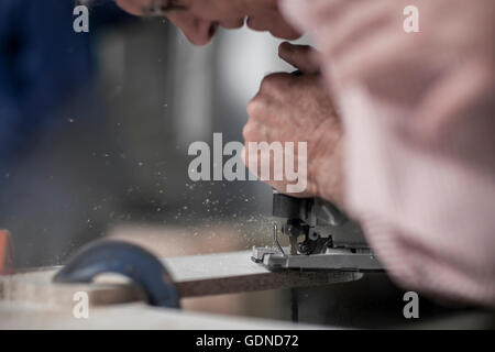 Cropped shot of senior carpenter using jigsaw tool in workshop Stock Photo