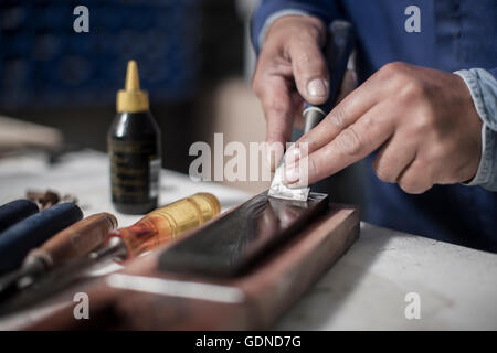 Close up of carpenter's hand using chisel in wood workshop Stock Photo