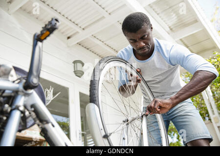 Man fixing bicycle in porch Stock Photo