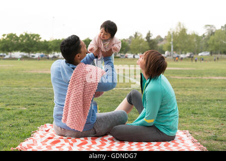 Couple playing with baby in park Stock Photo