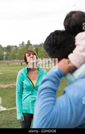 Couple playing piggyback ride with baby in park Stock Photo