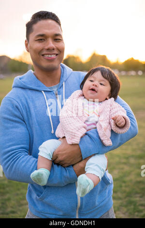 Father cradling baby in park Stock Photo