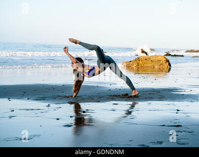 Young female dancer balancing on hand at beach, Los Angeles, California, USA Stock Photo