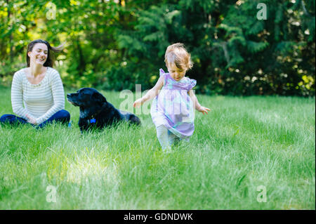 Female toddler running away from mother in park Stock Photo