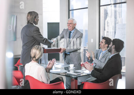 Businessmen shaking hands at conference table meeting, New York, USA Stock Photo