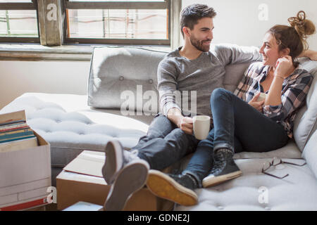 Moving house: Young couple relaxing on sofa surrounded by cardboard boxes Stock Photo