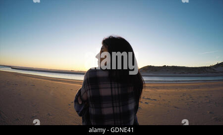 Rear view of woman wrapped in shawl looking away on Cannon Beach, Oregon, USA Stock Photo